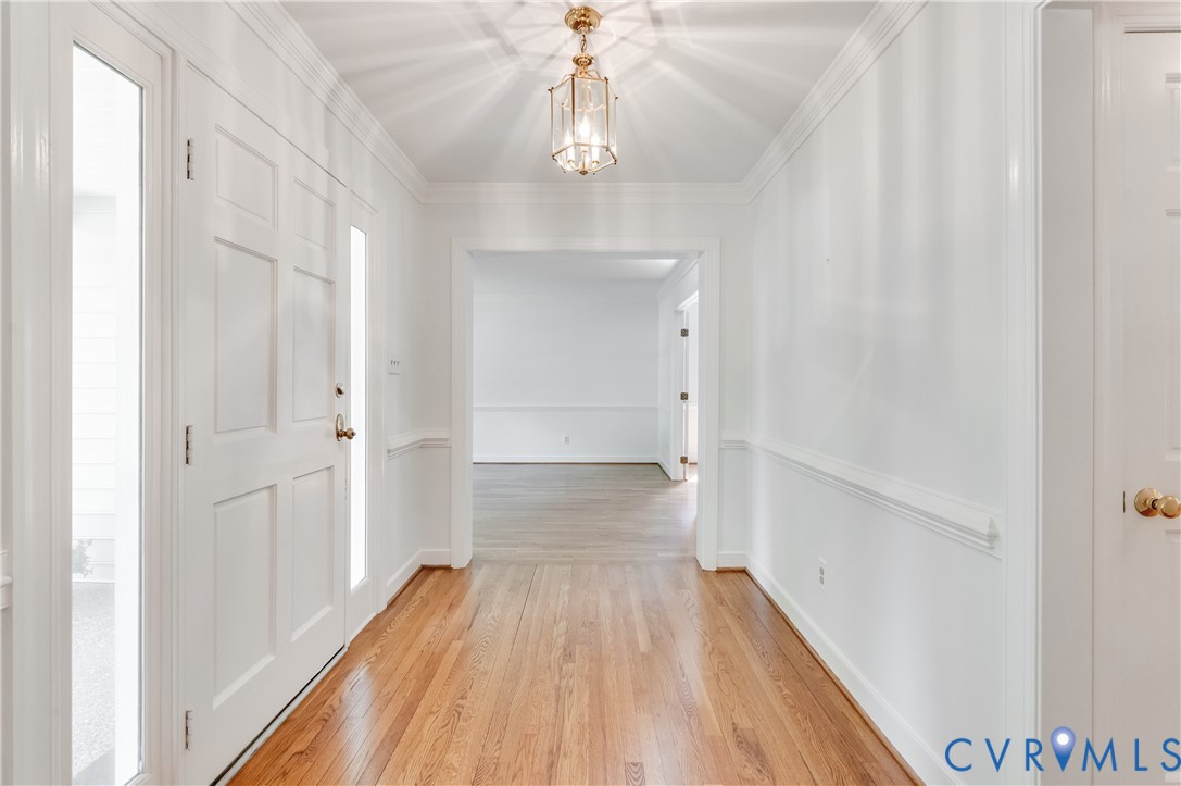 Entryway with wood-finish flooring, paneled front door, sidelight windows, and decorative chandelier Entryway with wood-finish flooring, paneled front door, sidelight windows, and decorative chandelier