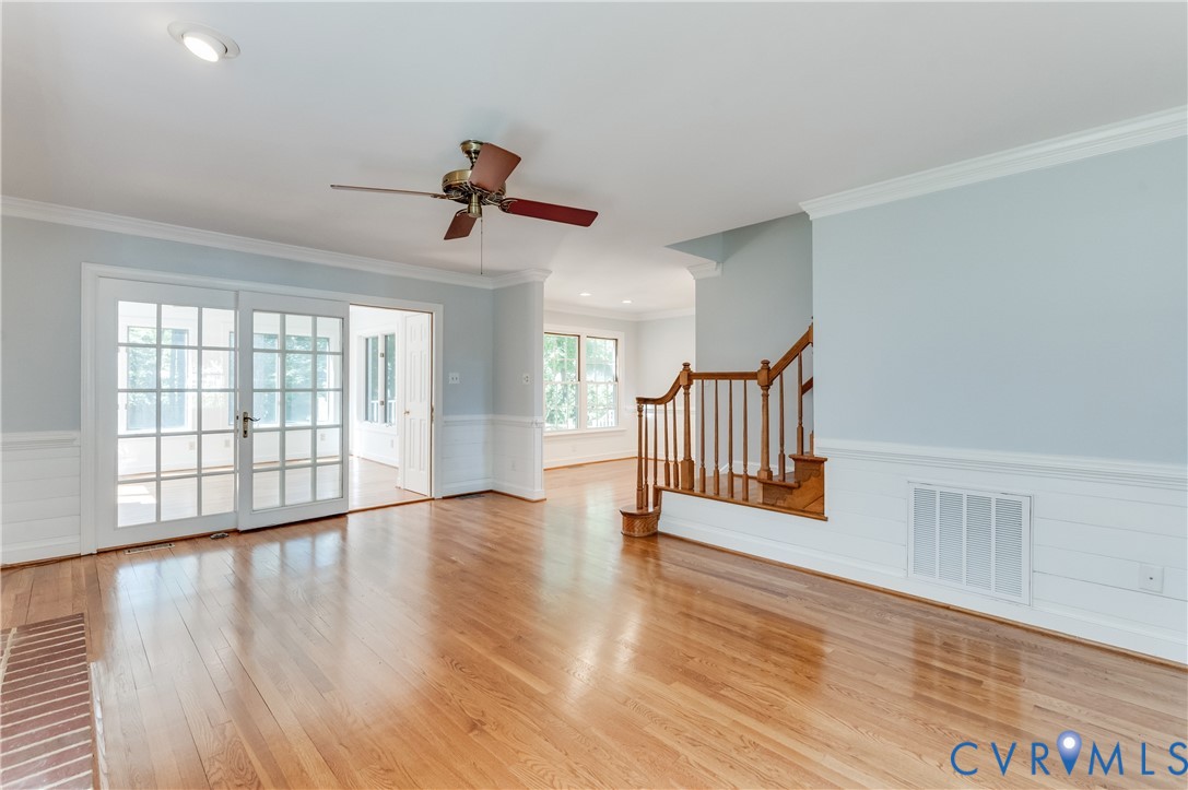 Hardwood flooring, recessed lighting, ceiling fan, wainscoting, and French doors