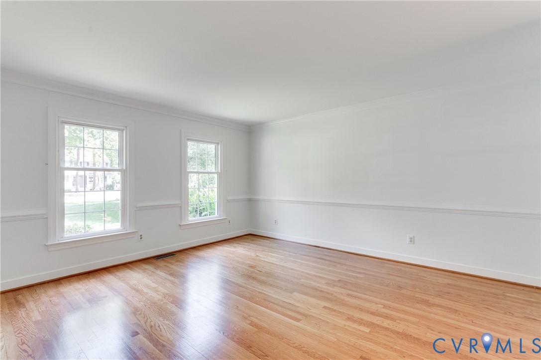 Hardwood flooring, white painted walls, two double-hung windows, chair rail molding, and crown molding