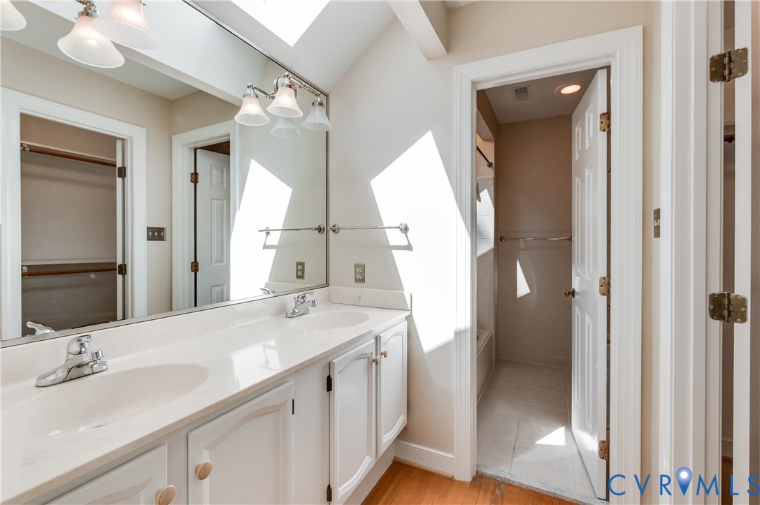 Dual vanity with undermount sinks, expansive wall-mounted mirror, and overhead lighting fixtures