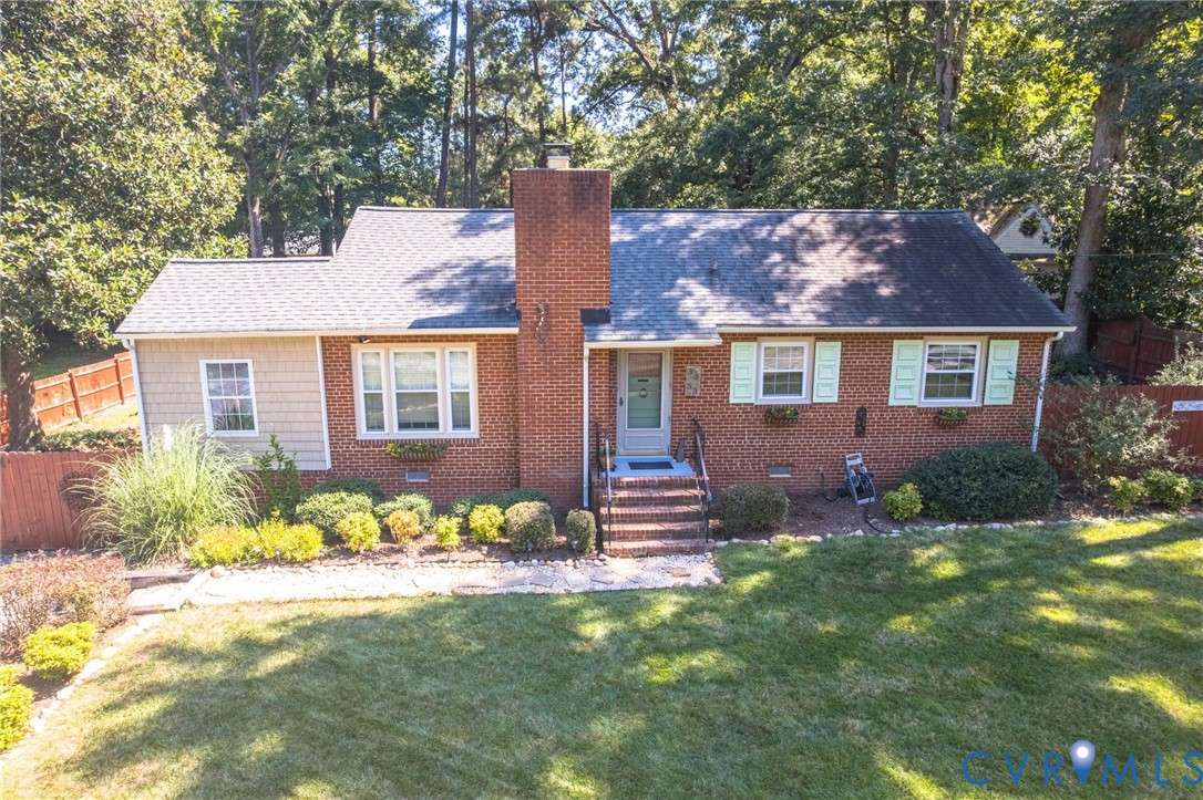 Brick exterior with a prominent brick chimney, light-colored roofing, and a front entry porch with steps