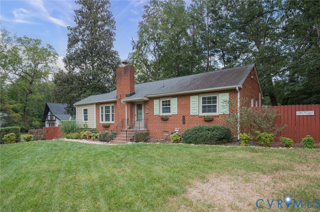 Brick exterior with a prominent chimney, light green shutters, and a front entry with handrails