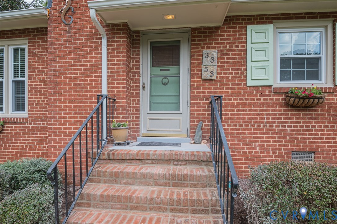 Brick exterior with white trim, green shutters, and a front entry door with a screen door