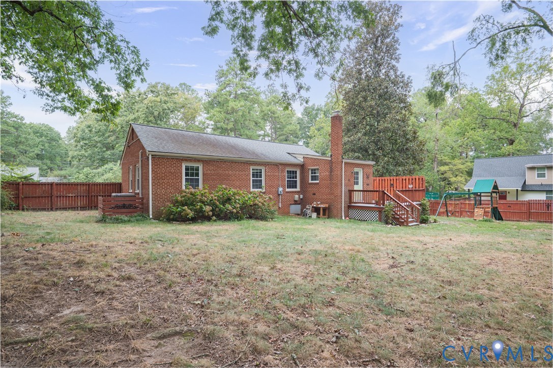 Brick exterior with a prominent chimney, wood deck, and wood privacy fencing