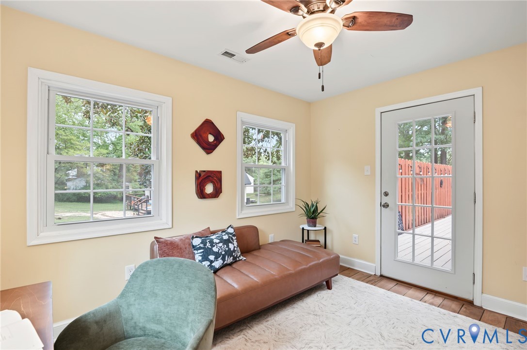 Recessed ceiling fan with integrated lighting, multiple windows providing natural illumination, wood-finish flooring, and a glass-paned exterior door