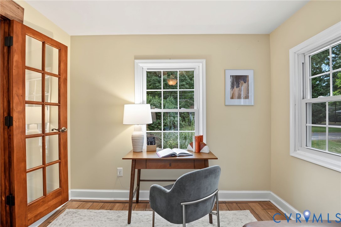 Wood-finish flooring, two large windows, and a wood-frame glass panel door