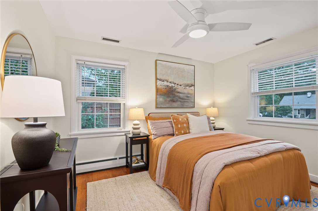 Hardwood flooring, two large windows with blinds, and a contemporary ceiling fan