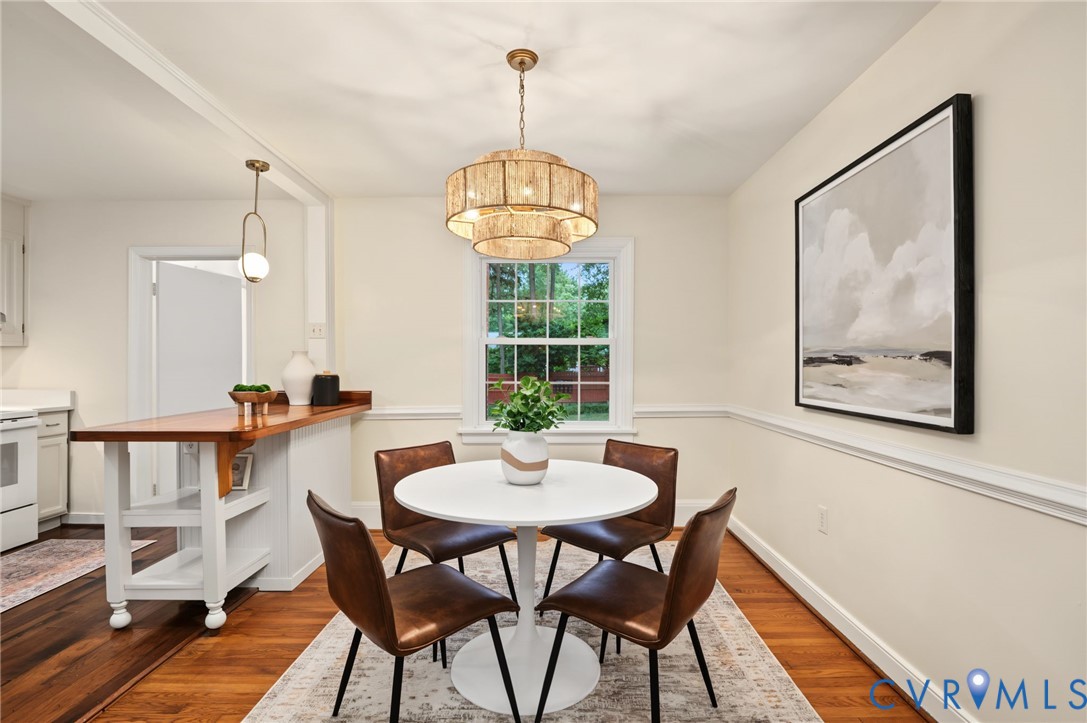 Hardwood flooring throughout, a multi-tiered chandelier, a built-in breakfast bar, and a window for natural illumination