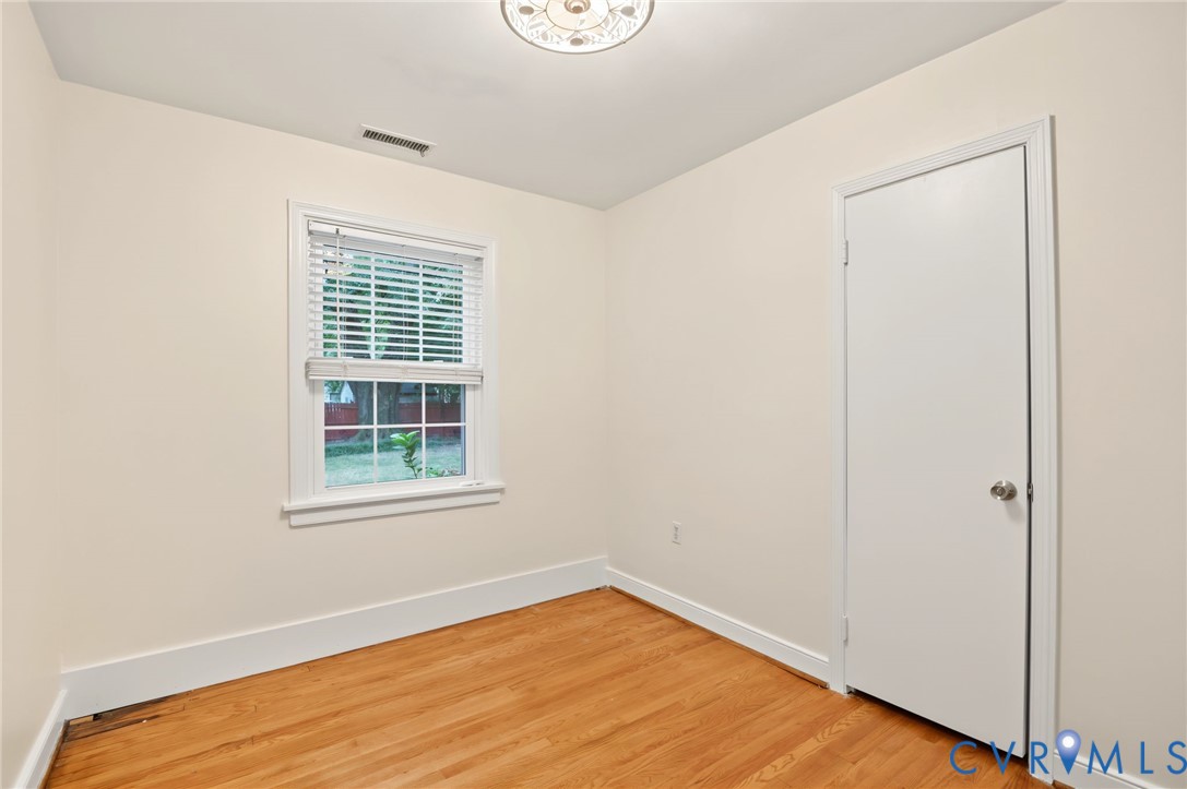 Light-toned walls, wood-finish flooring, white trim, and a flush mount ceiling light fixture
