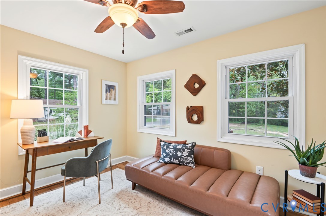 Multiple windows with white trim, wood-finish flooring, and ceiling fan with integrated lighting
