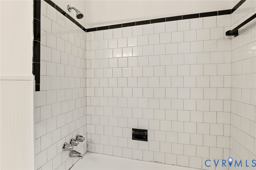 White subway tile shower surround with black accent trim and chrome fixtures