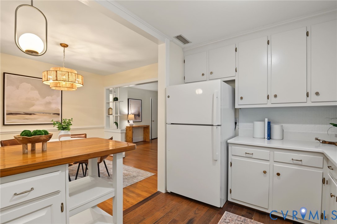 White cabinetry and appliances in the kitchen, with wood-finish flooring
