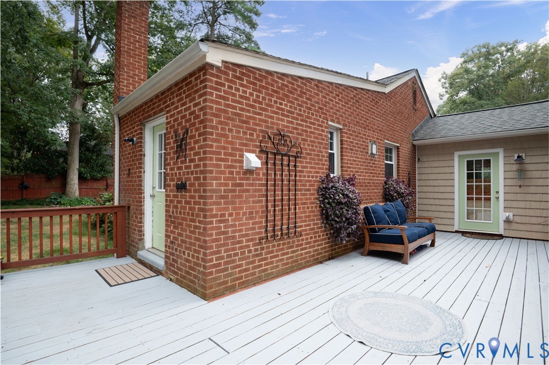 Spacious multi-level deck with white painted decking, brick exterior, and a light green French door