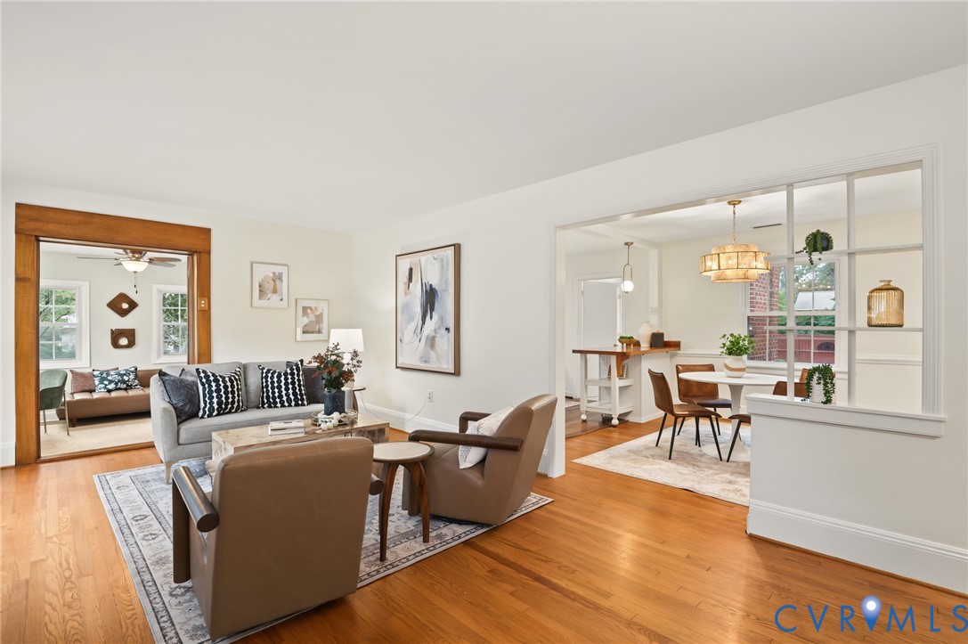 Hardwood flooring throughout, a wide cased opening with wood trim, and a partial wall with window-pane detailing Hardwood flooring throughout, a wide cased opening with wood trim, and a partial wall with window-pane detailing