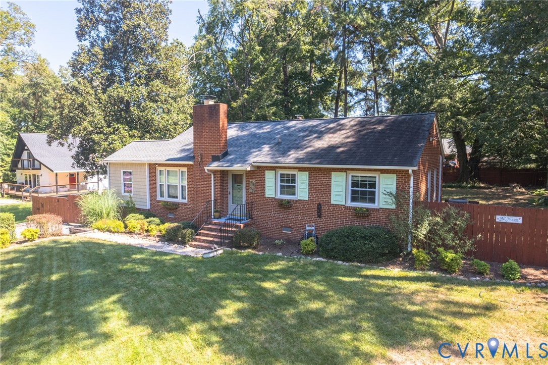 Brick exterior with shutters, a gabled roof, and a mature tree line