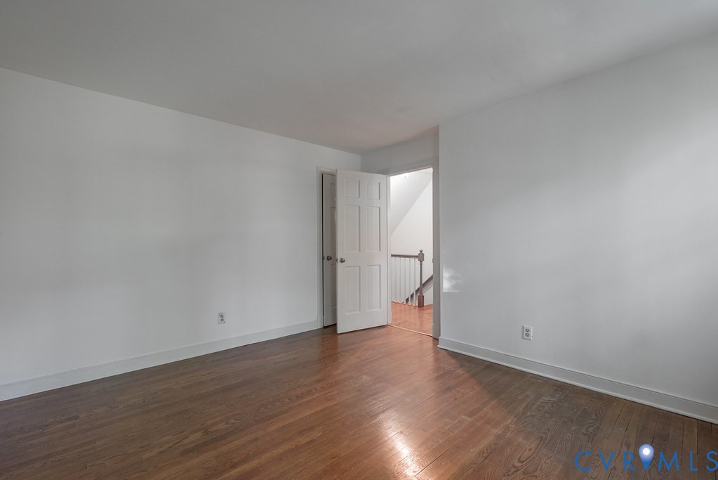 Hardwood flooring, white walls, and a white interior door