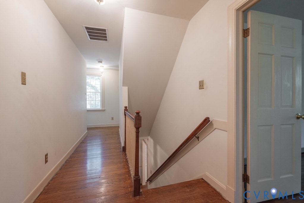 Hardwood flooring, painted interior door, window with natural light, painted walls, and wood banister