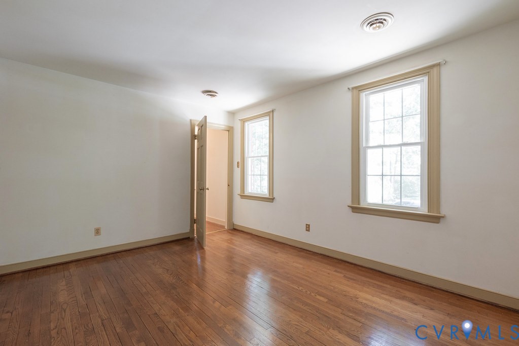 Hardwood flooring, painted walls, two double-hung windows, and ceiling lighting