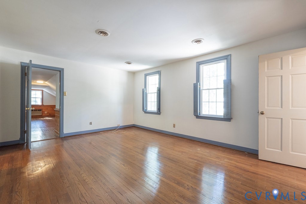 Hardwood flooring, two sash windows with interior shutters, paneled door, and recessed lighting