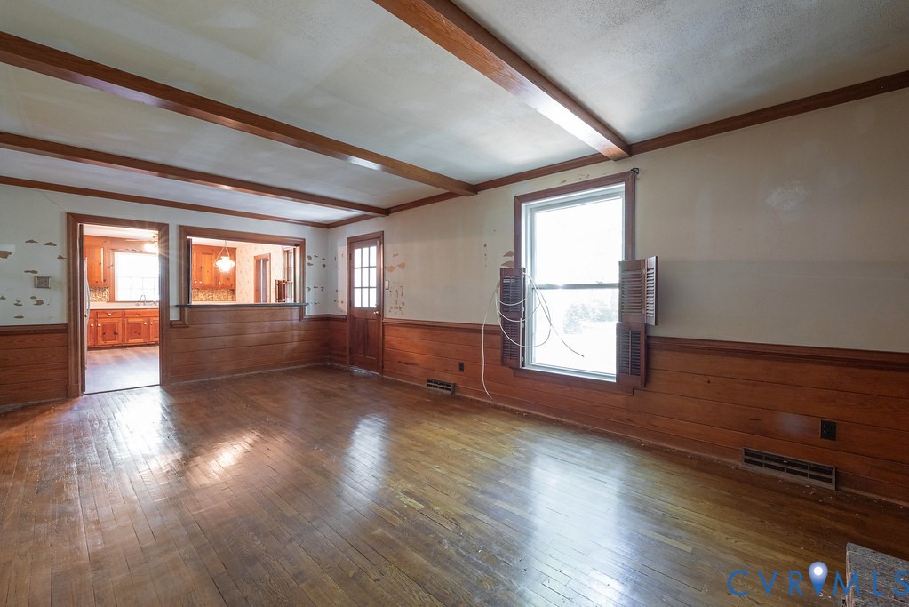 Exposed wood beam ceiling, wood-paneled walls, and wood-finish flooring