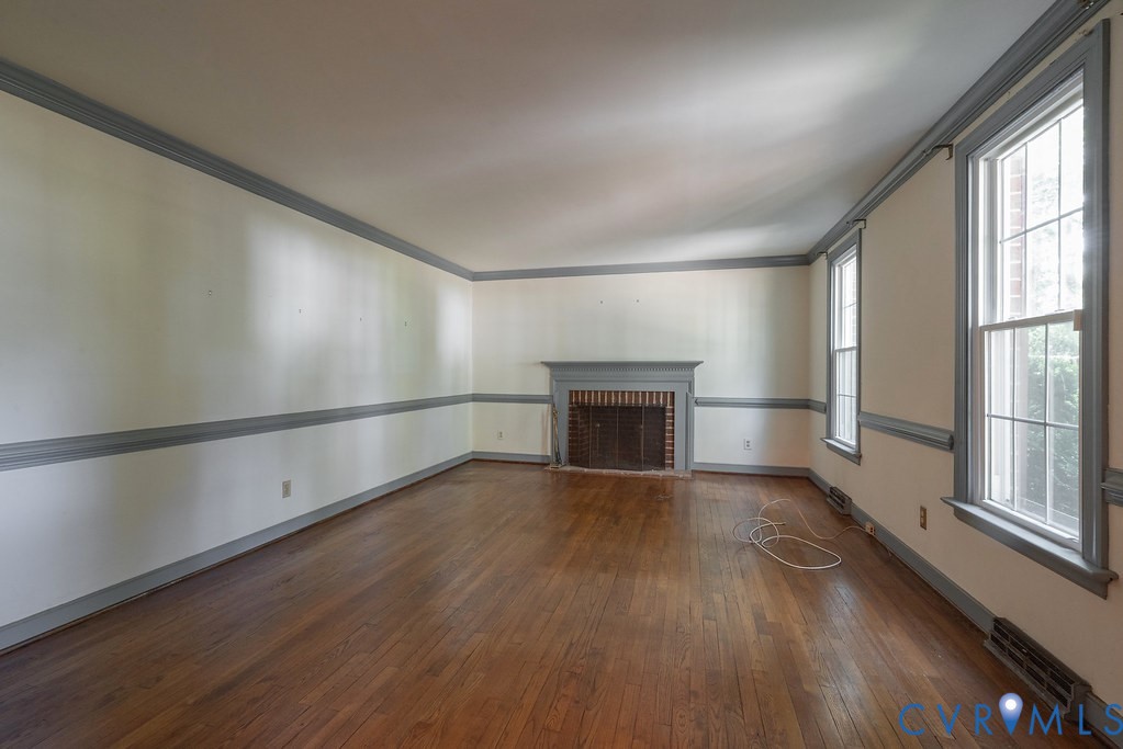 Hardwood flooring, decorative crown molding, chair rail molding, brick fireplace with a painted mantel, and multiple windows