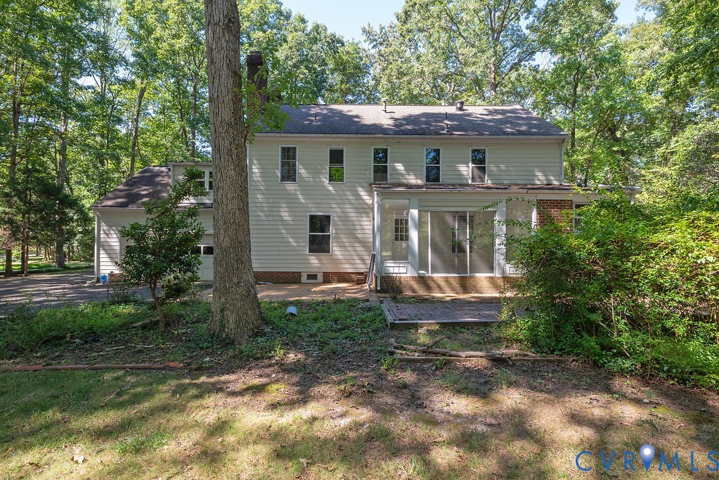 Two-story home with a multi-pane glass sliding door, an attached garage, and surrounding mature trees