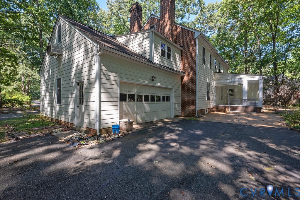 Asphalt driveway leading to an attached garage with a paneled door