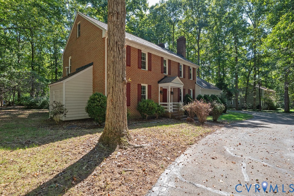 Brick exterior with red shutters, covered entry porch, and attached storage shed