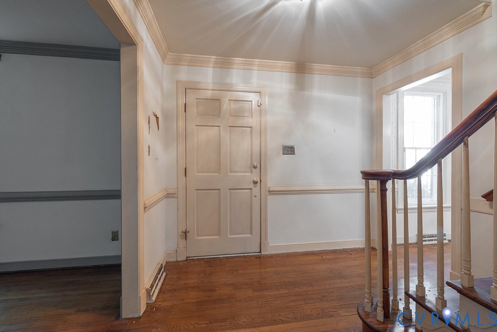 Hardwood flooring throughout, detailed crown molding, wainscoting, and a multi-panel interior door