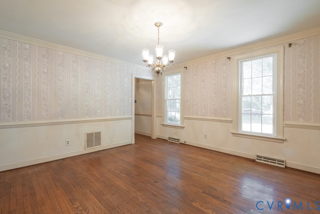 Hardwood flooring, decorative wallpaper, white trim, crown molding, and two double-hung windows