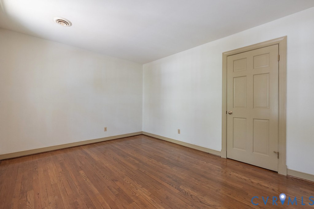 Hardwood flooring, painted interior door, neutral wall color, and ceiling-mounted air vent
