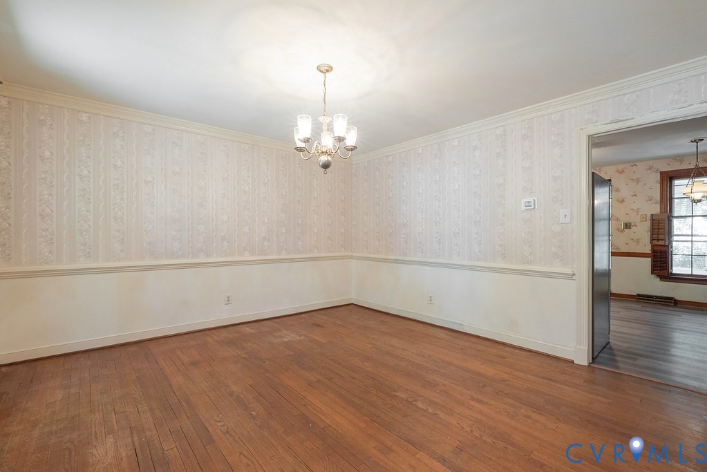 Hardwood flooring, decorative wallpaper, crown molding, chair rail molding, and a chandelier