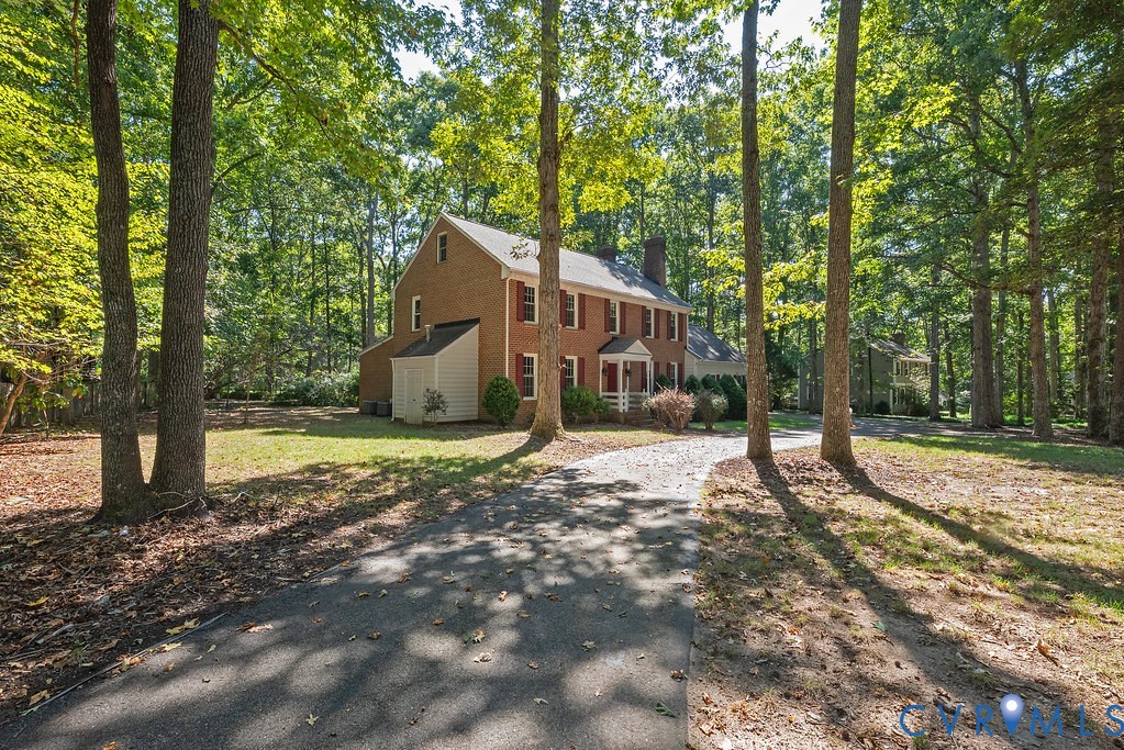 Brick exterior with white trim, arched portico, and red shutters