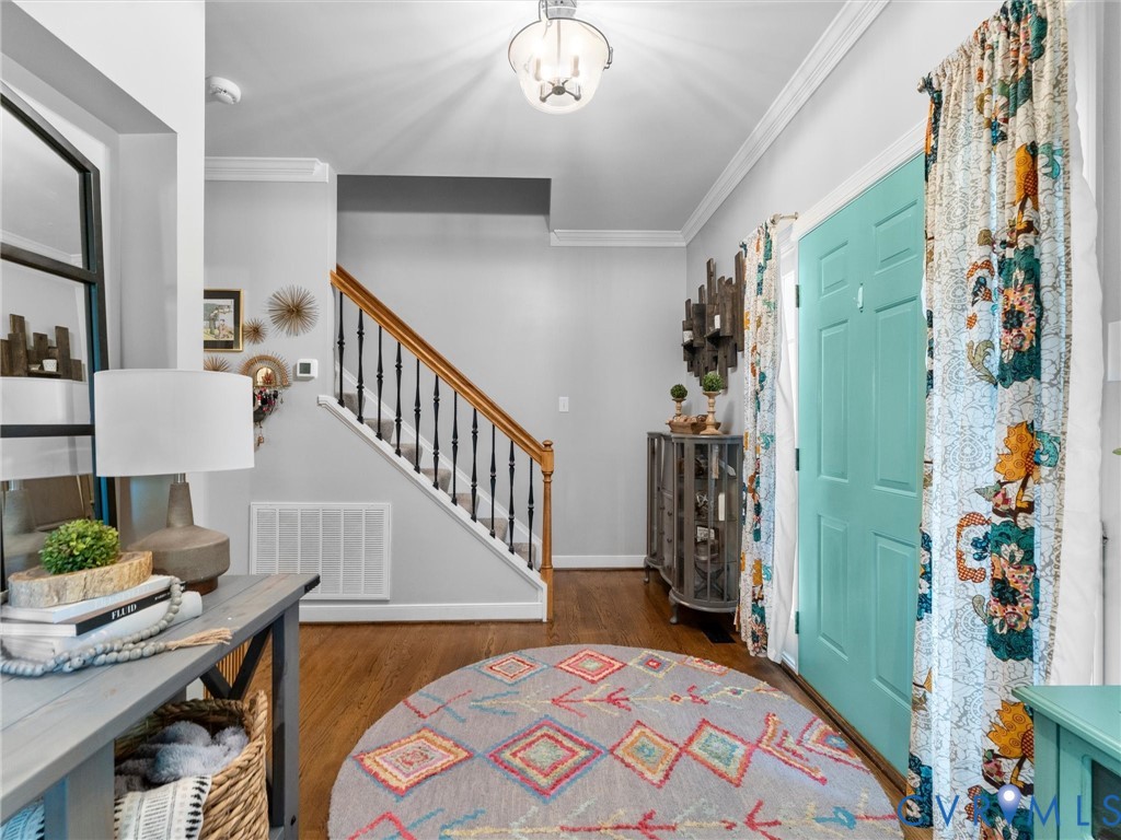 Open and inviting foyer with hardwood flooring, crown molding, coat closet, and powder room Open and inviting foyer with hardwood flooring, crown molding, coat closet, and powder room