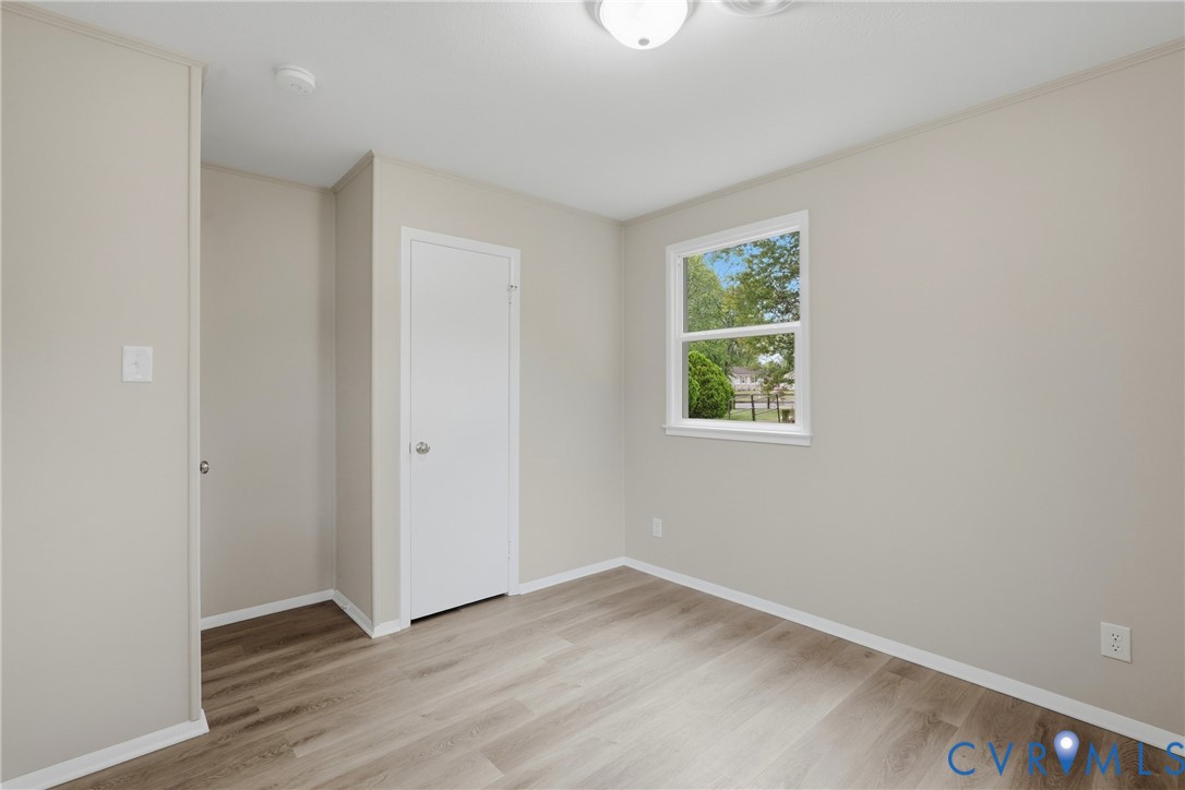Wood-finish flooring, neutral wall tones, white trim, and a double-hung window
