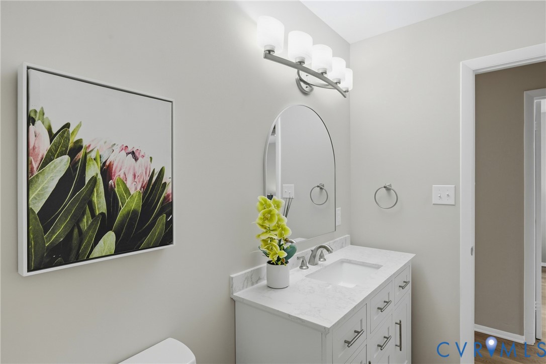 Vanity with an integrated sink, brushed nickel faucet, arched mirror, and white cabinetry