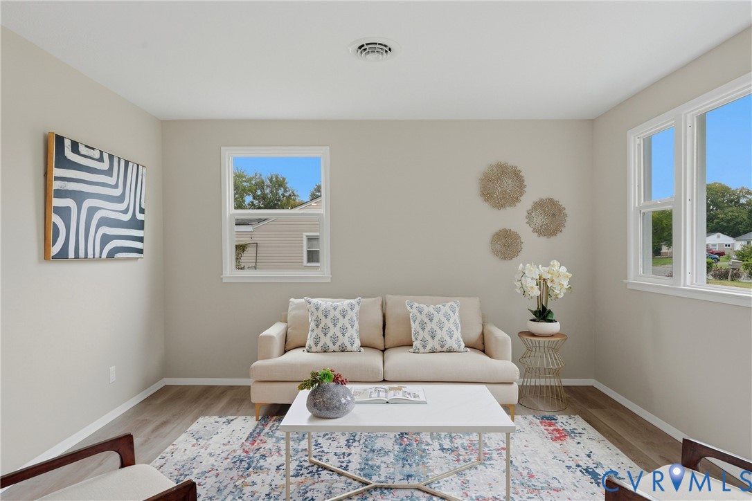 Neutral wall tones, wood-finish flooring, and multiple windows create a bright ambiance