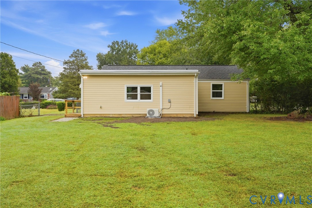 Expansive green lawn with a wood fence and a small wood-finish deck
