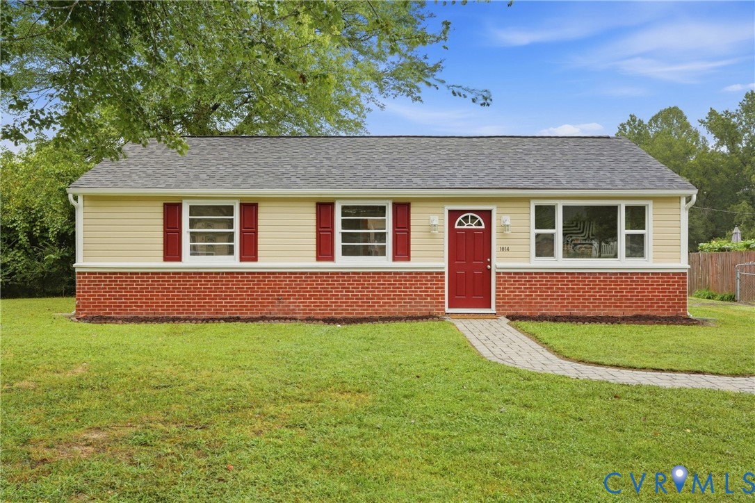 Ranch-style residence featuring a red brick foundation, light-colored siding, and a gray shingle roof Ranch-style residence featuring a red brick foundation, light-colored siding, and a gray shingle roof
