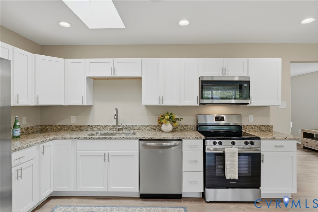 White shaker-style cabinetry with stainless steel hardware, granite countertops, and a full suite of stainless steel appliances