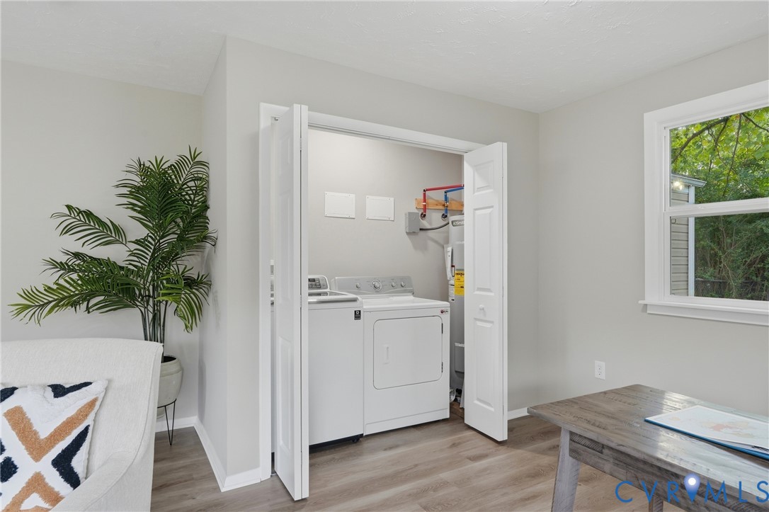 Laundry closet with bi-fold doors, wood-finish flooring, and a single window