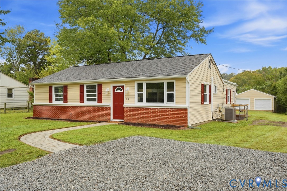 Light yellow siding with red brick accent, red shutters, and a red entry door