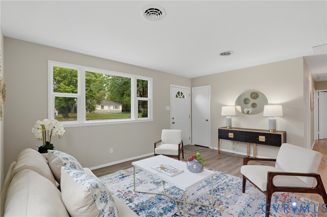 Neutral wall tones, wood-finish flooring, a multi-pane window, and a white entry door with a decorative glass insert
