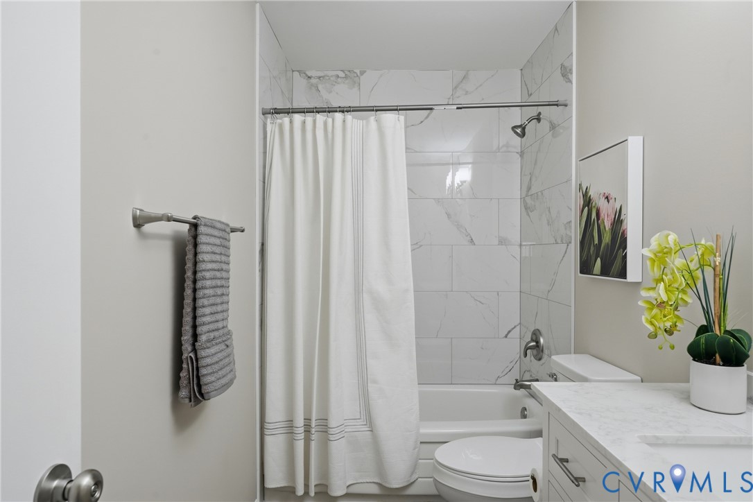 Modern bathroom featuring a frameless glass-enclosed shower with marble-look tile surround, white subway tile walls, and chrome fixtures