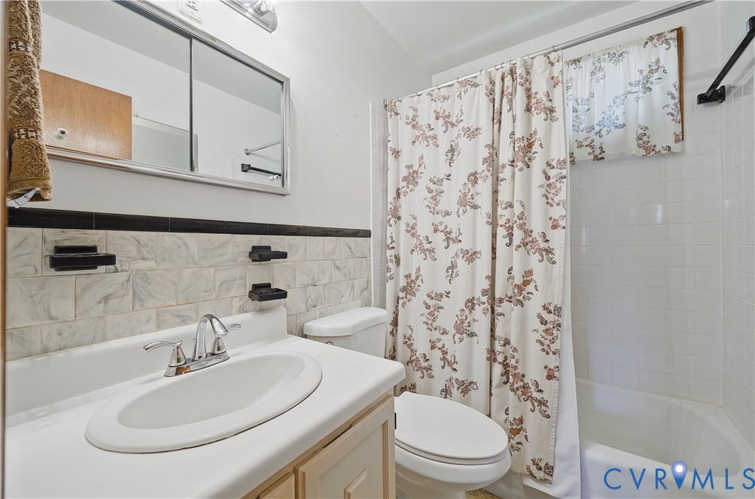 Bathroom featuring a wall-mounted medicine cabinet, white tiled bathtub surround, and a vanity with a drop-in sink