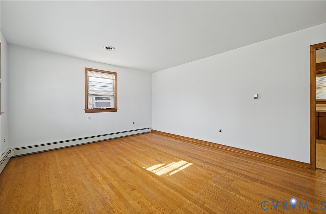 Hardwood flooring, painted walls, window with wood trim, and a window air conditioning unit