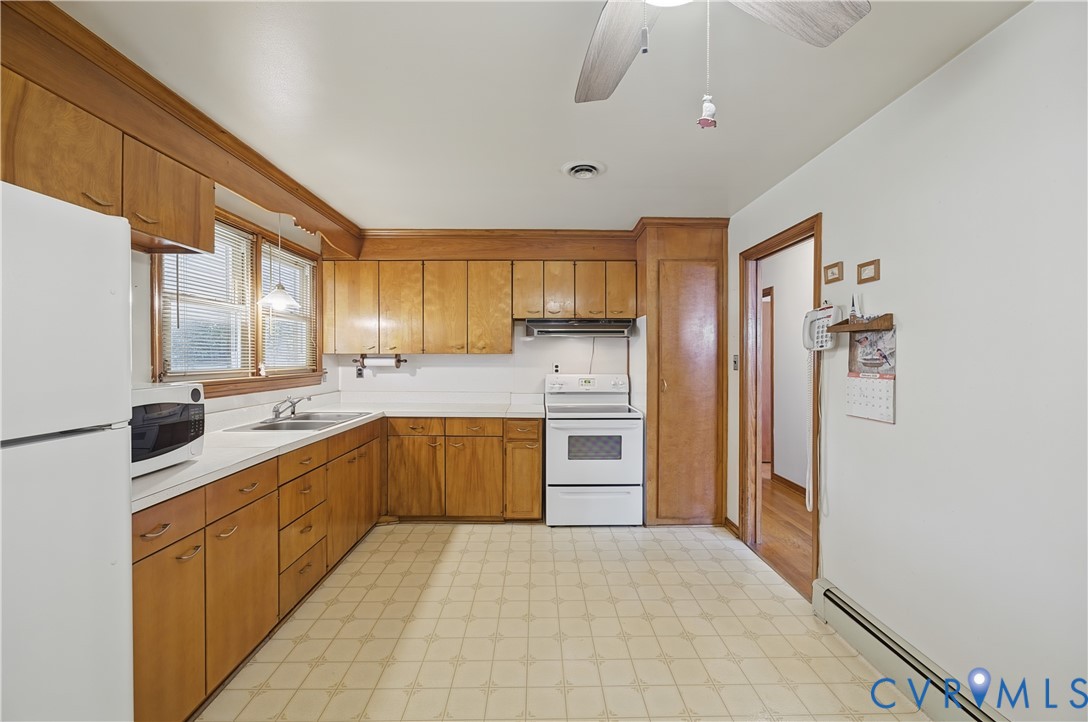 Kitchen featuring wood-finish cabinetry, white countertops, a double basin sink, and a white electric range