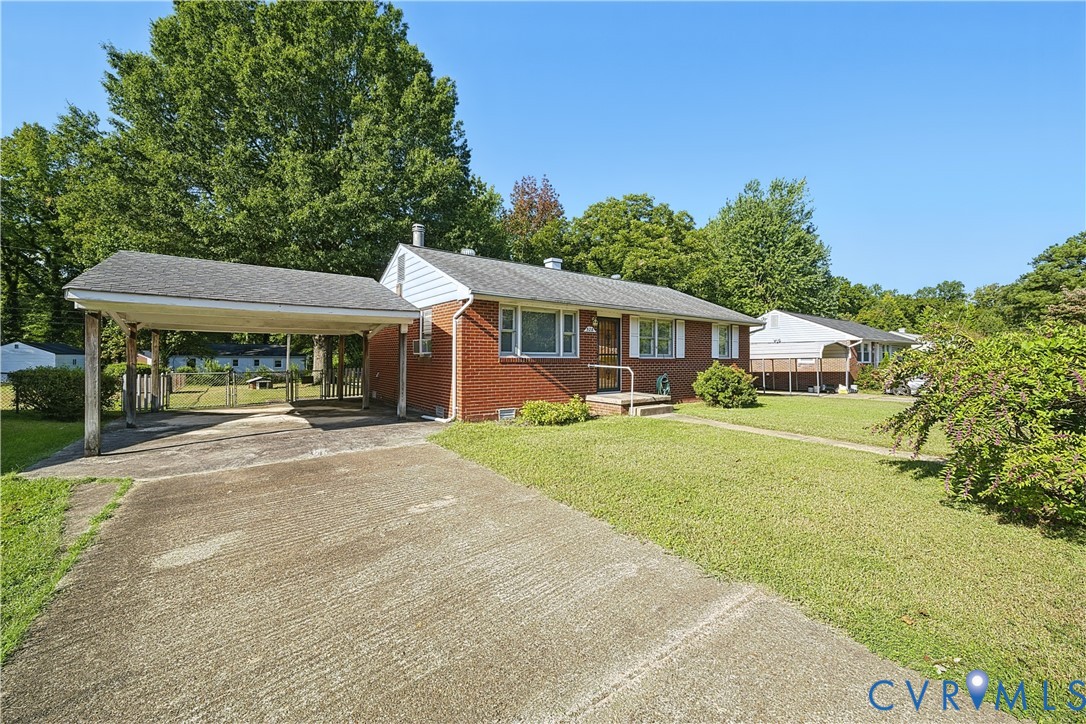 Brick exterior with carport, paved driveway, and established landscaping