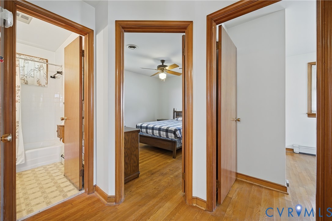 Hardwood wood-finish flooring throughout this hallway and adjoining spaces, framed by warm wood-trimmed doorways