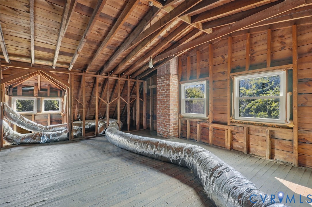 Exposed wood framing, brick chimney, and multiple windows
